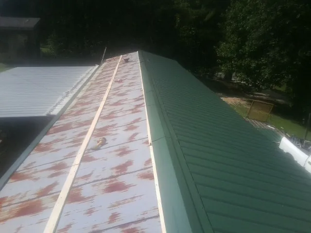 Old rusted panels beside newly installed green metal roofing — Wind Damage Roof Repair by Roofing Brothers in Milton Freewater