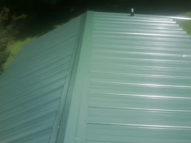 New green metal panels meeting at the ridge of a roof — Flat Roof Repair work by our crew in Milton Freewater