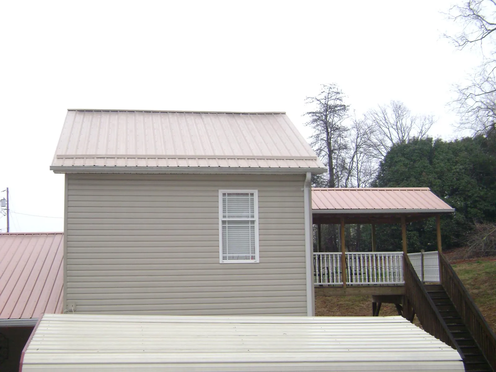 Tan metal roofs on a two story addition and attached porch, from a Roof Replacement job in Milton Freewater