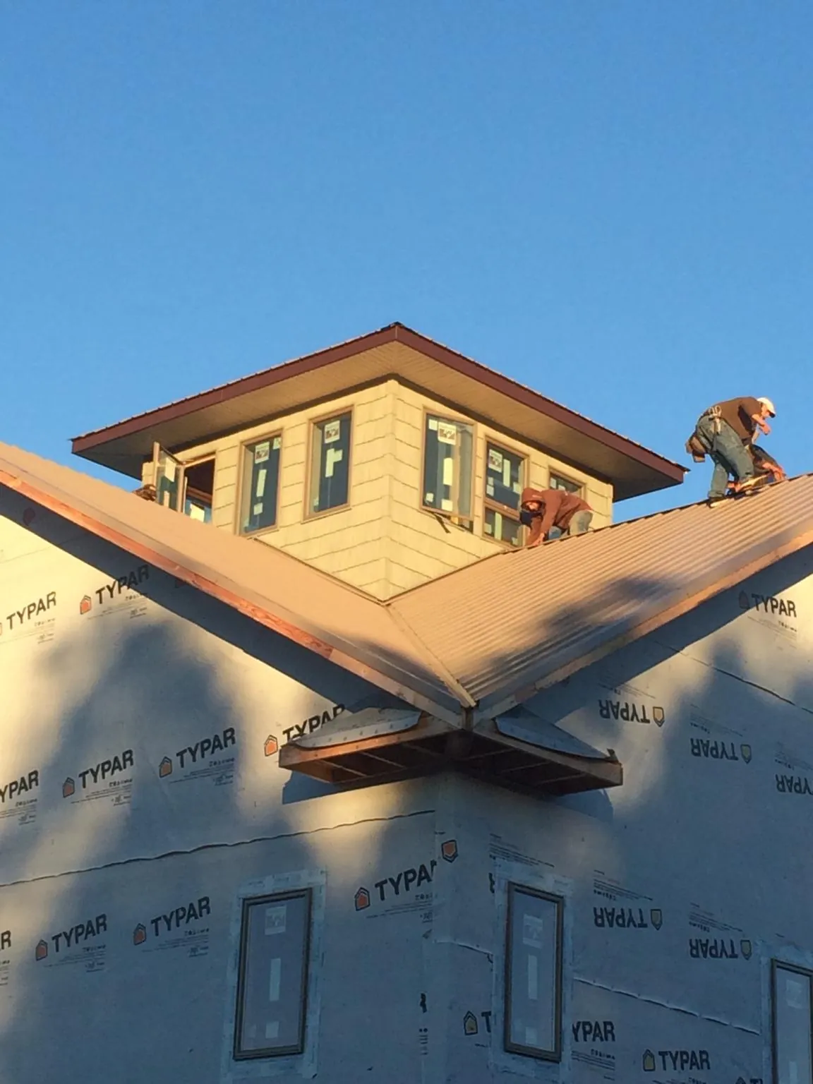 Roofers working around a rooftop cupola on a new metal roof at sunset — Roof Waterproofing in Milton Freewater by Roofing Brothers